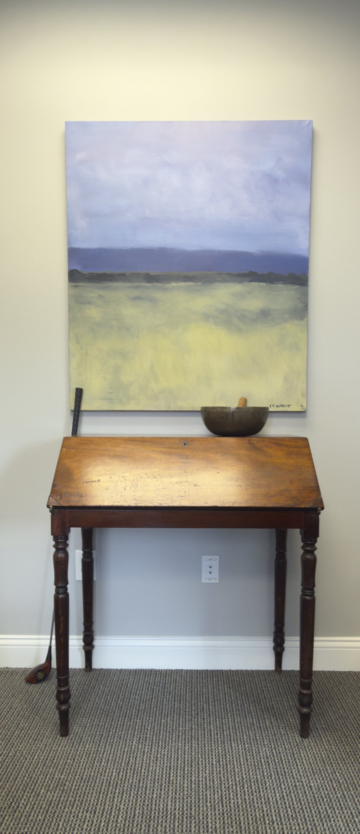 An antique writing desk beneath a landscape painting in the practice